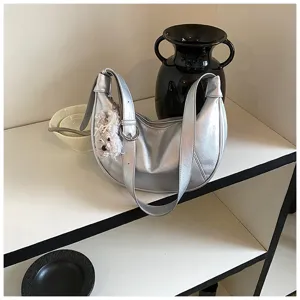 Dettaglio borsa a spalla metallica argentata, elegante borsa hobo con simpatico ciondolo cucciolo.