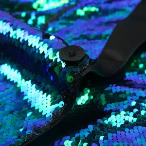 Close-up detail of men's blue green sequin stage performance jacket showing texture and button.