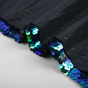 Detailed shot of men's stage suit lapel with vibrant blue green sequins and black fabric.