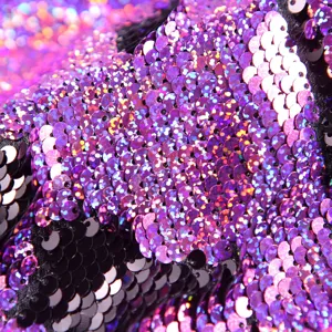 Close-up detail of purple and black reversible sequins fabric, glittering reflective texture.