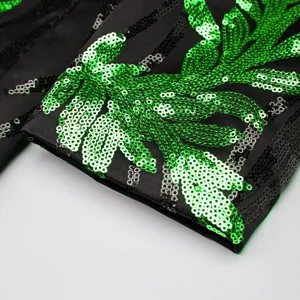 Close-up detail of black mens blazer featuring vibrant green sequin leaf applique.