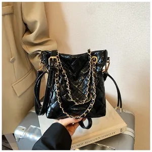 Black quilted bucket bag detail showcasing metallic gold chain straps and glossy leather finish.