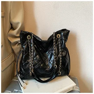 Closeup of black quilted tote bag with gold chain straps, premium texture for daily commuting.