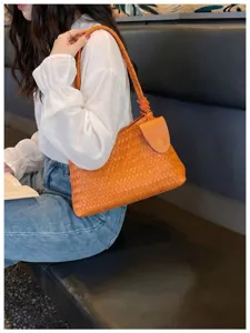 Detailed close-up of the orange woven leather shoulder bag highlighting premium fashion texture.