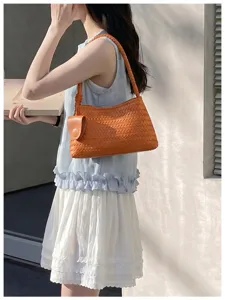 Detailed view of orange woven shoulder bag, elegant intrecciato design for women fashion.