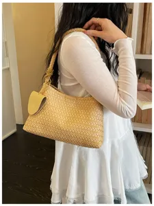 Detailed view of fashionable yellow woven leather shoulder underarm bag with node.