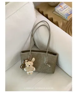 Detail view of a stylish minimalist tote bag featuring a cute knit bear charm and clean design.
