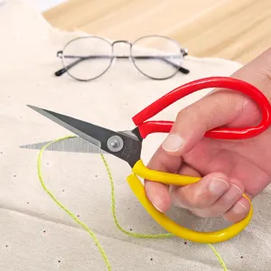 Professional tailor scissors with ergonomic red yellow handles for precise fabric cutting.