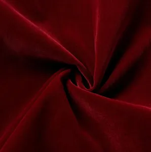 Wine red velvet fabric material detail showing soft texture and elegant glossy sheen close up.