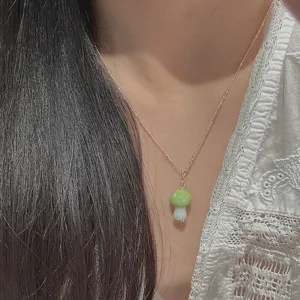 Primer plano del lindo collar con colgante de champiñón verde usado, mostrando detalles.
