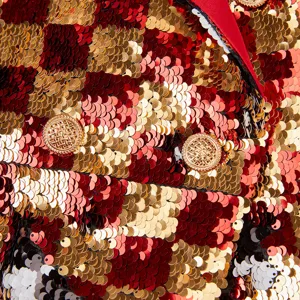 Primer plano del tejido de lentejuelas bicolor de lujo y los botones metálicos dorados del blazer.