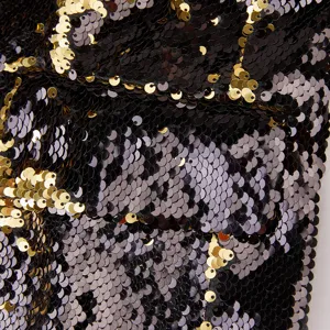 Primer plano detallado de la textura de tela de lentejuelas reversibles bicolor negra y dorada.