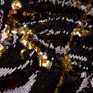 Primer plano del detalle de tela con lentejuelas reversibles en negro y oro, brillante.