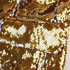Primer plano detallado del tejido de lentejuelas bicolor de lujo, acabado en oro y plata.