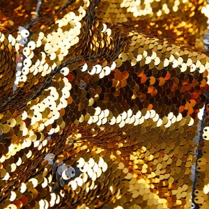 Primer plano detallado de tela de lentejuelas doradas lujosas y brillantes con efecto reflejo.