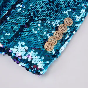 Detalle de manga de blazer de lentejuelas azules con elegantes botones dorados.
