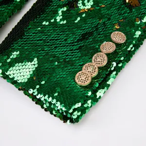 Detalle de manga de chaqueta de lentejuelas verdes botones dorados, primer plano.