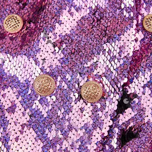 Impresionante detalle en primer plano de tela de blazer con lentejuelas y botones dorados.