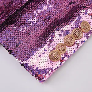 Detalle en primer plano de puño de blazer de lentejuelas para mujer con degradado y botones dorados.