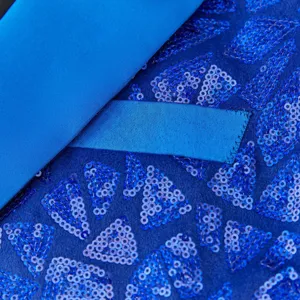 Blue sequin suit jacket detail close-up, luxury party stage performance fabric.
