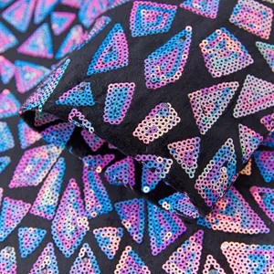 Close-up detail of men's stylish sequin suit fabric featuring vibrant iridescent geometric triangle patterns.