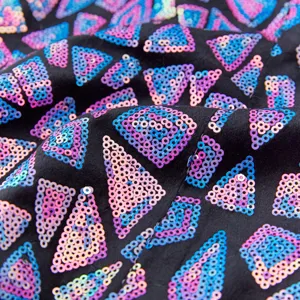 Close-up detail of shimmering triangular sequins on black fabric for party apparel.