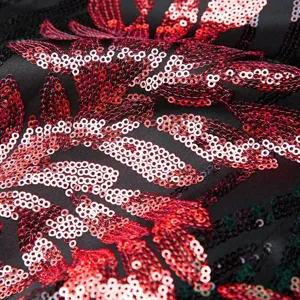Detailed view of black fabric with sparkling red sequin floral embroidery pattern.