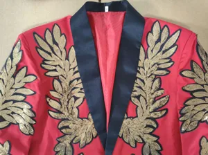 Detalle de aplique de hoja de lentejuelas doradas en el cuello del blazer de hombre rojo