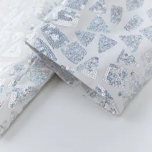 Detail shot of men's white sequined suit jacket cuff featuring silver geometric patterns.