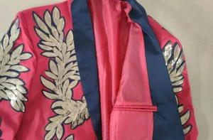 Vista de detalle de una chaqueta de traje roja para hombre con apliques de lentejuelas doradas.