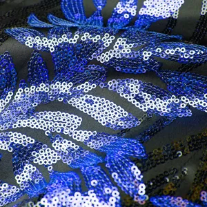 Close-up detail of luxury blue and black sequin fabric with sparkling leaf embroidery.