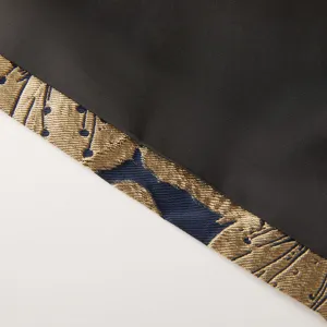 Détail de tissu de costume jacquard, motif rétro or et bleu avec texture noire.