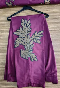 Vista detallada de pantalones burdeos para hombre con bordado de hojas de lentejuelas doradas.