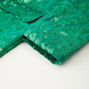 Close-up view of green sequin suit jacket sleeve showing geometric triangle texture.