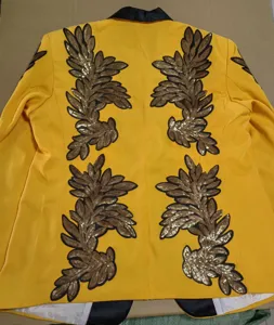 Chaqueta de traje amarilla para actuaciones con brillante bordado de lentejuelas doradas en la espalda.