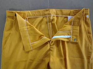 Detalle de la cintura del pantalón de traje amarillo para hombre, cierre de cremallera fino.