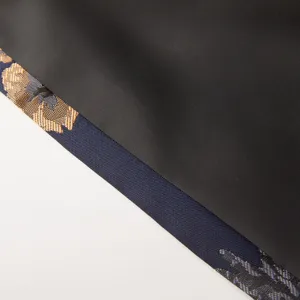Gros plan sur le détail du revers de costume en jacquard avec tissu noir et bordure élégante.