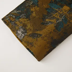 Vue détail tissu jacquard rétro, motif floral doré métallique et vert foncé texturé.