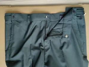 Vista detallada de pantalón formal de hombre, pantalón verde oscuro con cremallera y trabillas.