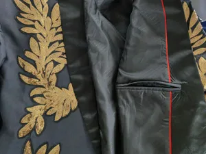 Primer plano de chaqueta negra de hombre con bordado de lentejuelas doradas y bolsillo interior.