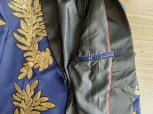 Vista detallada de chaqueta de traje azul para hombre con bordado de lentejuelas doradas.