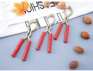 Close-up detail of multi-functional metal nutcracker with red handle for walnut peeling.