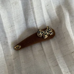 Gros plan d'une pince à cheveux en tissu marron avec pendentif chien léopard stylé.