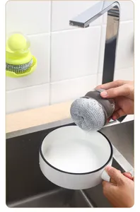 Detail view of the liquid dispensing dish cleaning brush in kitchen sink use scene.