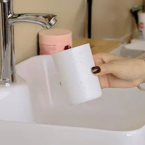 Vue rapprochée d'un gobelet à brosse à dents en plastique blanc près du lavabo.