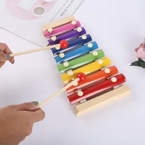 Detailed view of a colorful wooden 8-note xylophone toy with mallets being played by hands.