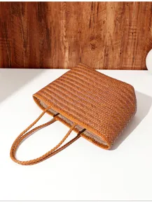 Vista in primo piano della borsa tote in pelle intrecciata marrone con eleganti manici intrecciati.