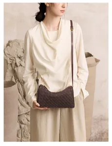 Close-up detail of dark brown woven cylindrical shoulder bag with elegant leather texture.