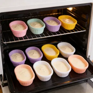 Stampini da forno in silicone colorato riempiti di impasto, disposti ordinatamente nel forno.