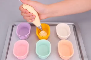 Dettaglio stampo da forno in silicone con pirottini per muffin colorati riempiti.